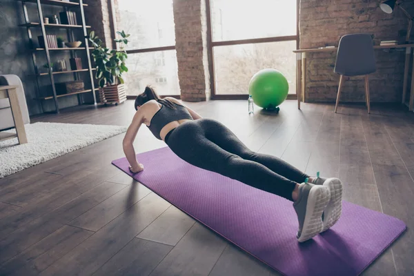 Plná velikost zpět zadní páteř pohled fotografie aktivní motivované krásné sportovní dívka dělá praxi jóga aerobik push-up na podlaze mat oblečení kalhotky gumboty v domě vnitřní — Stock fotografie