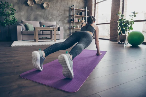 Plná délka zpět zadní páteř pohled fotografie sportovec krásná dívka dělá push@-@ ups aerobik prkno praxe úsilí fyzické cvičení na podložce oblečení kalhotky v domě uvnitř — Stock fotografie