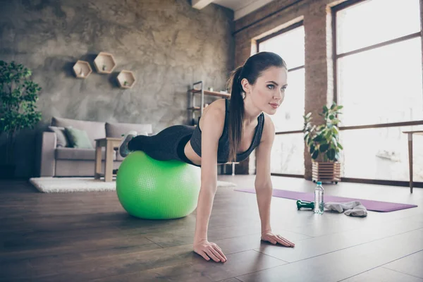 Profil fotografie krásné dámy karantény hobby trénink domácí dynamické pilates strečink nohy na fit míč prkno cvičení pro všechny svalové skupiny stojí na pažích obývací pokoj — Stock fotografie