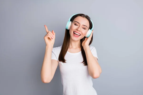 Retrato de chica excitada sincera entusiasta escuchar música de estilo disco con auriculares inalámbricos quieren danza subir índice dedo cerrar los ojos usar buen traje de aspecto aislado sobre fondo de color gris — Foto de Stock