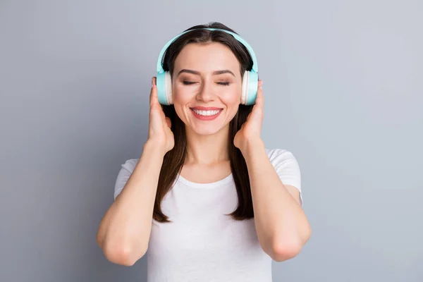Porträt einer positiven fröhlichen Jugend Mädchen halten drahtlose Headset hören Disco-Stil Musik fühlen zufrieden Gesichtsausdruck tragen gut aussehende Kleidung isoliert über graue Farbe Hintergrund — Stockfoto
