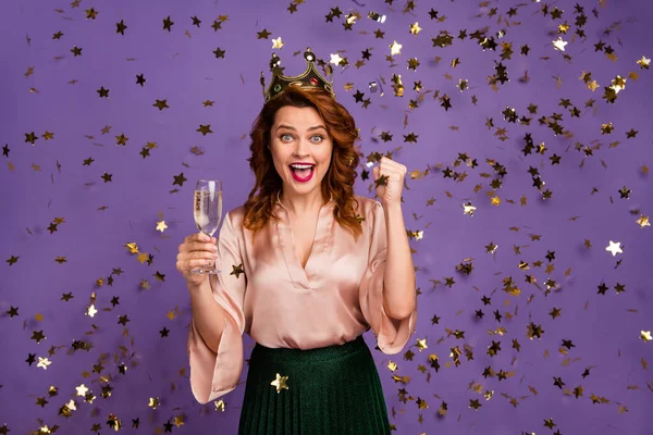 Pozitivní radost dívka mají bakalářská promoce akce držet šampaňské sklo těšit vyhrát tiára zvýšit pěsti křičí nosit zelenou sukně blůza izolované světlé fialové barvy pozadí konfety létat — Stock fotografie