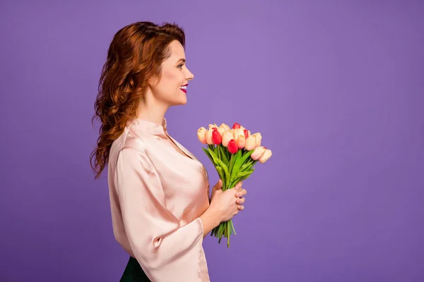 Foto de perfil de la encantadora señora bonita sostienen ramo de flores frescas de tulipán 8 partido de marzo que recibe agradable presente desgaste de lujo camisa beige blusa aislada de color púrpura fondo — Foto de Stock