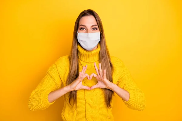 Πορτρέτο της αυτή ωραία ελκυστική υγιή κορίτσι φορώντας μάσκα ασφαλείας που δείχνει το σημάδι της καρδιάς σταματήσει τη μόλυνση γρίπη mers ασθένεια cov ασθένεια απομονωθεί πάνω από φωτεινό κίτρινο χρώμα φόντο — Φωτογραφία Αρχείου