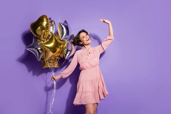 Ritratto di candida dolce ragazza carina tenere molti palloncini che ottiene come regalo di laurea mano onda salutare i suoi ammiratori spazio vuoto indossare buon look vestito isolato su sfondo di colore vibrante — Foto Stock