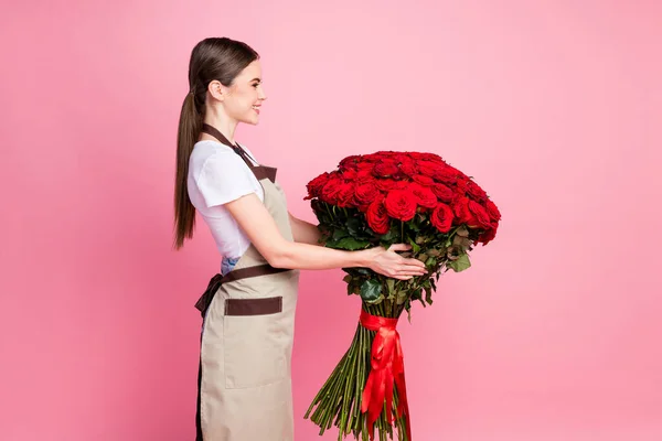 Perfil vista lateral retrato dela ela agradável atraente linda menina alegre segurando em mãos grande buquê de rosas vermelhas fazendo presente venda varejo isolado sobre cor pastel rosa fundo — Fotografia de Stock