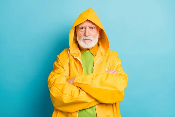 Close-up portrait of his he nice serious grey-haired man fisherman wearing yellow overcoat folded arms bad weather news forecast isolated on bright vivid shine vibrant blue color background — Stock Photo, Image