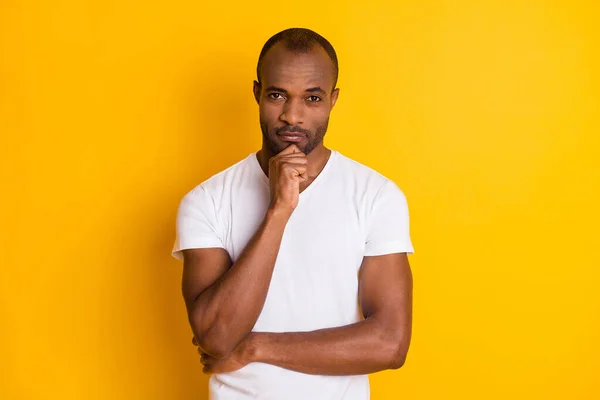 Foto de atractivo chico de piel oscura sostenga el brazo en la barbilla hombre de negocios seguro de sí mismo persona inteligente desgaste casual camiseta blanca pantalones vaqueros azules aislados brillante color amarillo vivo fondo —  Fotos de Stock