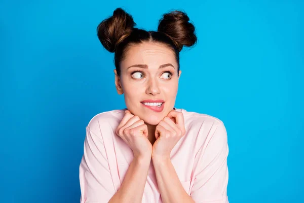 Foto de primer plano de la atractiva expresión asustada bastante loca dama dos bollos labios mordiendo mirada espacio vacío aterrorizado miedo ojos desgaste casual blanco rosa camiseta aislado color azul fondo — Foto de Stock