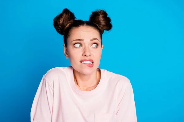 Närbild foto av attraktiva ganska roligt uttryck dam två bullar bita läppar ser tomt utrymme skräckslagen rädsla ögon bära casual vit rosa t-shirt isolerad blå färg bakgrund — Stockfoto