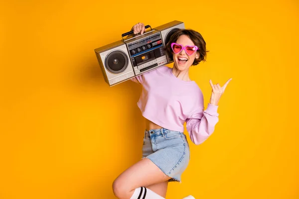 Si ', regole rock. Positivo allegro ragazza tenere boom box ascoltare giovani musica spettacolo dita corna simbolo urlo gioire usura rosa maglione jeans isolato su brillante brillantezza colore sfondo — Foto Stock