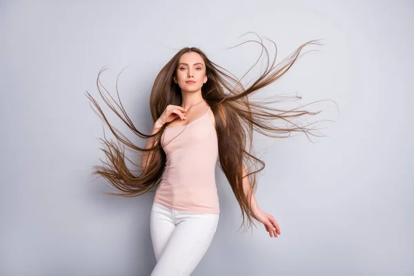 Photo of attractive charming lady demonstrating ideal groomed long healthy hairstyle flying on air after salon procedure wear beige singlet white pants isolated grey color background