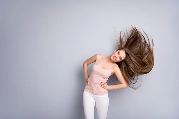 Foto van aantrekkelijke model dame demonstreren ideale verzorgde lange gezonde kapsel vliegen op lucht na salon procedure armen door zijkanten dragen beige singlet broek geïsoleerde grijze kleur achtergrond — Stockfoto