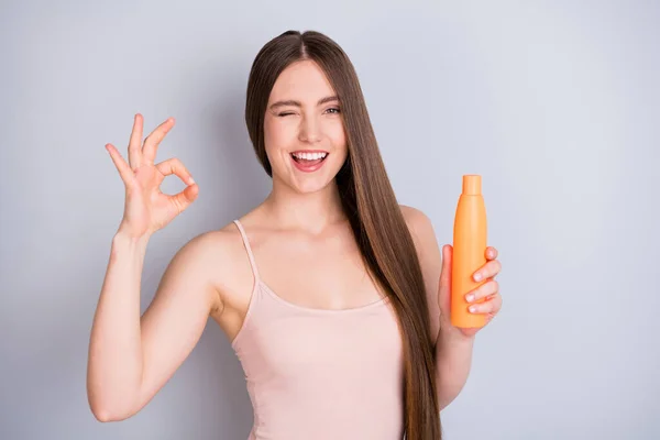 Close-up portrait of her she nice-looking attractive pretty cheerful cheery brown-haired girl holding in hand cream bottle showing ok-sign extra length isolated on light gray pastel color background — Stock Photo, Image