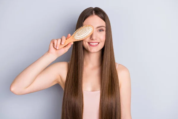 Foto van aantrekkelijke perfecte verschijning model dame lange verbazingwekkende kapsel verbergen een oog favoriete houten kam speelse stemming slijtage beige singlet geïsoleerde grijze kleur achtergrond — Stockfoto