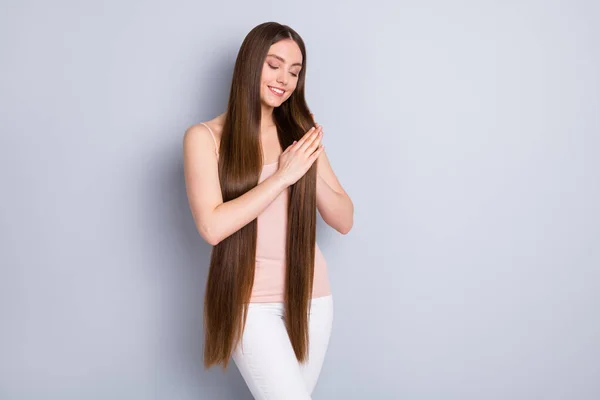 Foto van verbazingwekkende dame insmeren handen zetten vloeibare zijde masker ideaal nette lange gezonde kapsel haarverzorging concept dragen beige singlet witte broek geïsoleerde grijze kleur achtergrond — Stockfoto