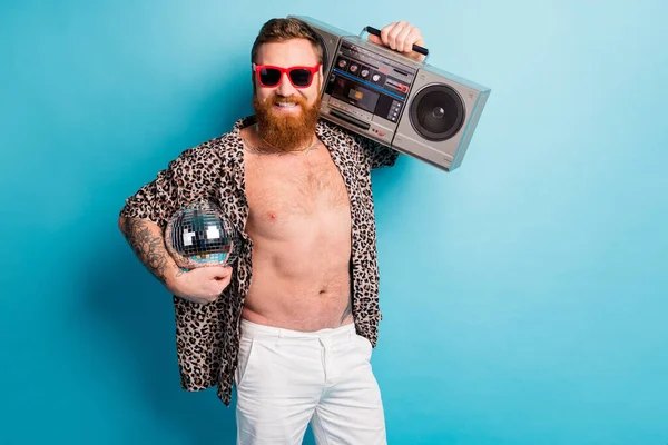 Foto van koele macho man naakt romp zonnige hete dag houden retro tape recorder schouder glitter disco bal chill rest partij dragen shorts luipaard shirt zon specs geïsoleerde blauwe achtergrond — Stockfoto