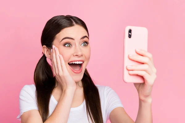 Foto de primer plano de la señora bastante alegre sostener las manos del teléfono emociones emocionadas leer comentarios positivos brazo en la mejilla desgaste casual camiseta blanca aislado pastel color rosa fondo —  Fotos de Stock