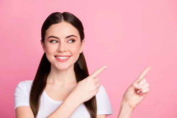 Närbild foto av ganska rolig dam lång frisyr svansar direkta fingrar tomt utrymme visar intressant nyhet produkt bära casual vit t-shirt isolerad pastell rosa färg bakgrund — Stockfoto