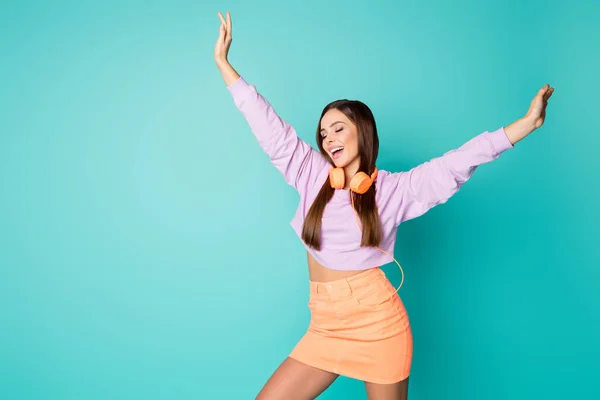 Foto von niedlichen schönen Millennial Dame hören moderne Technologie Kopfhörer tanzen überglücklich heben Hände Jugend bewegt tragen abgeschnittenen violetten Pullover orange Rock isoliert teal Farbe Hintergrund — Stockfoto