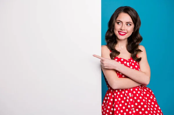 Foto de gerente atraente senhora dirigindo dedo lado banner anúncio vazio propondo oferta novidade desgaste verão vermelho branco pontilhado retro vestido isolado azul cor fundo — Fotografia de Stock