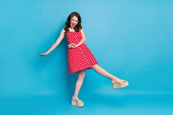 Foto de cuerpo completo de la atractiva señora bonita de buen humor levantar las manos de las piernas bailando los estudiantes de fiesta de verano rojo blanco punteado vestido retro zapatos de los dedos de los pies abiertos aislados de color azul de fondo —  Fotos de Stock