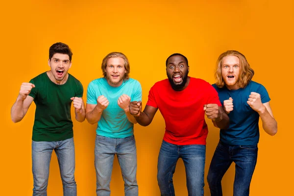 Фото сфокусированных фанки четырех мужчин студент смотреть футбольный матч сборной команды поддержки держать кулаки ухо футболка джинсы изолированы на ярком фоне — стоковое фото