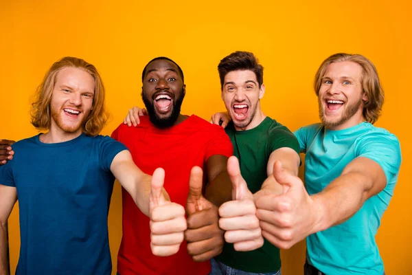 Portrét energických kamarádů čtyři muži show palec nahoru symbol těšit vynikající ideální víkend prodej promo reklamy nosit tričko izolované přes živé barevné pozadí — Stock fotografie