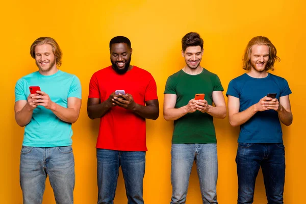 Фото четырех человек, юноши используют смартфон читать новости социальных медиа репост поделиться комментариями носить футболки джинсы джинсы Джинсы изолированы на ярком светлом фоне — стоковое фото