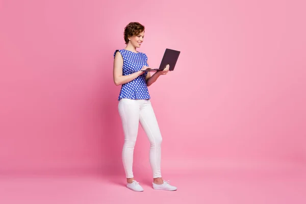 Longitud completa tamaño del cuerpo vista de ella ella agradable atractivo precioso enfocado alegre alegre alegre chica de pelo ondulado sosteniendo en las manos ordenador portátil ver vídeo aislado sobre fondo de color pastel rosa —  Fotos de Stock