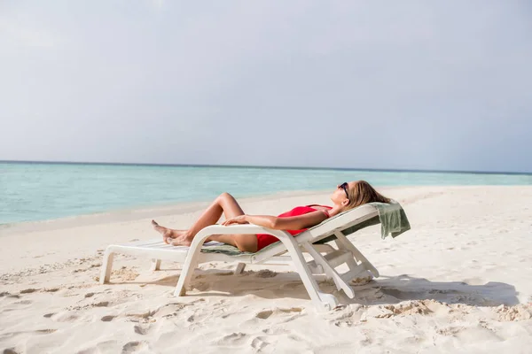 Ganzes Profilfoto der schönen friedlichen Dame liegend Liegestuhl azurblaues Wasser exotischen Ort leer Wüstenstrand Sonnenbaden tragen Sonne Spezifikationen roten Body genießen Sonnenstrahlen Ozean draußen — Stockfoto