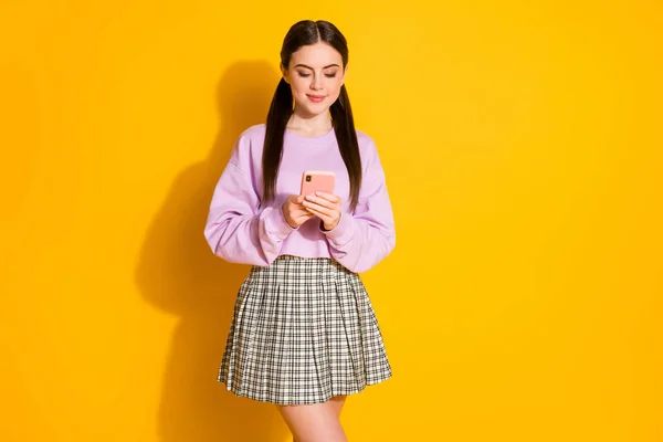 Портрет позитивної милої молодої дівчини використовує смартфон, слідуючи новинам соціальних мереж носіння картатого одягу ізольовано на яскравому фоні кольору блиску — стокове фото