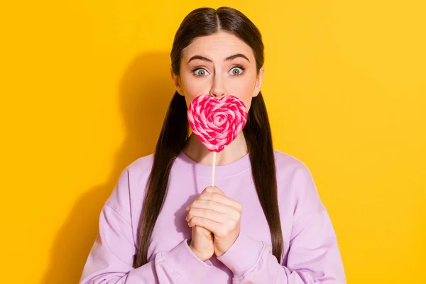 Retrato de chica divertida asombrada cerrar cubrir sus labios con sabrosa forma de corazón caramelo lolipop desgaste jersey aislado sobre fondo de color brillante —  Fotos de Stock