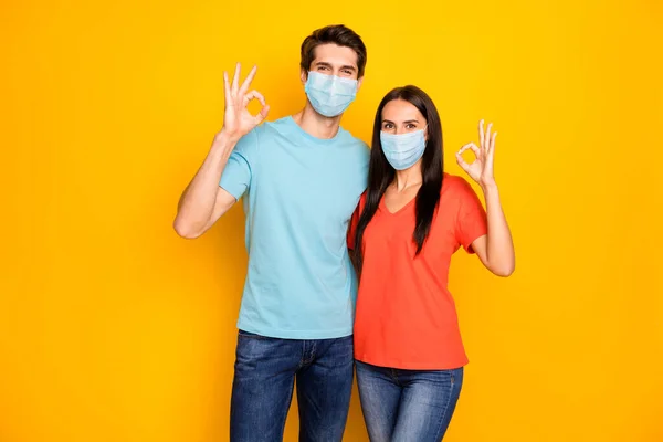 Портрет его она она прекрасная здоровая пара парень леди обнимает показывая окей-знак носить марлю безопасности маска остановить Mers CoV инфекции гриппа заражения изолированы на желтом фоне — стоковое фото