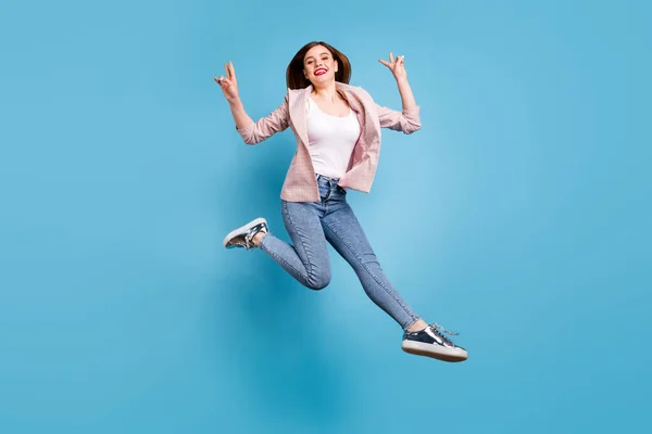 Plné tělo fotografie veselá krásná hezká dívka skok, aby v-znamení nosit kostkované sako tenisky izolované přes modré barvy pozadí — Stock fotografie