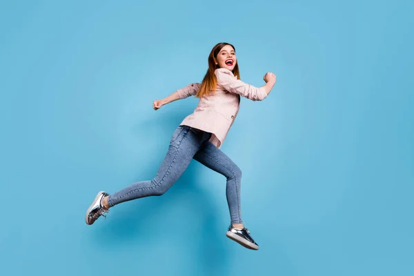 Full kropp profil sida foto av glada flicka hoppa springa snabbt efter vårsäsongen rabatter bära rutiga outfit gummiskor isolerade över blå färg bakgrund — Stockfoto