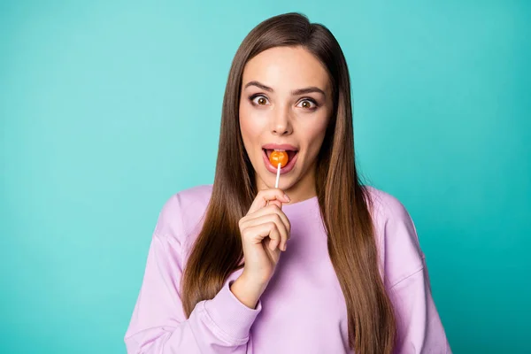 Foto av ganska rolig dam hålla klubba händer gott humör sötsaker beroende person slicka bita välsmakande godis slitage violett pullover isolerad livlig teal färg bakgrund — Stockfoto