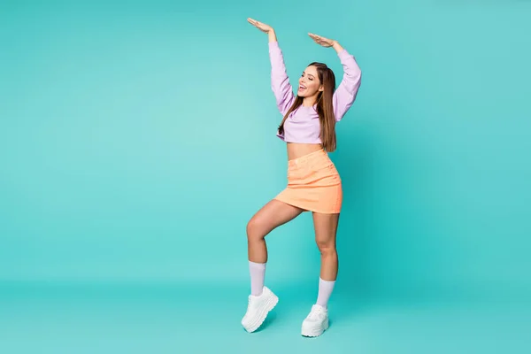 Foto de tamaño completo de funky cool señora loca levantar brazos fiesta danza movimiento juvenil desgaste púrpura suéter recortado desnudo abdomen naranja falda zapatos calcetines aislados color verde azulado fondo — Foto de Stock