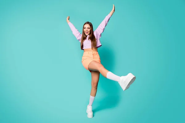 Volledige lengte foto van funky koele dame verhogen been armen genieten feest dans jong beweegt dragen paars bijgesneden trui naakt buik oranje rok schoenen sokken geïsoleerde teal kleur achtergrond — Stockfoto