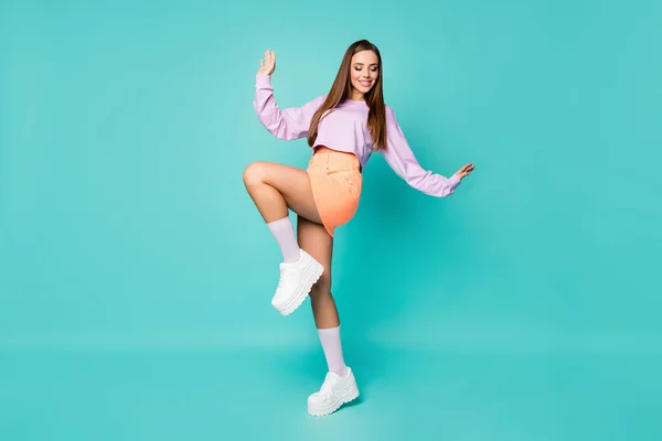 フルボディプロフィール写真のファンキークールな女性は足を上げる良い気分楽しむパーティーダンス若者の動き着用紫クロップドセーターオレンジスカート靴長いソックス隔離されたティール色の背景 — ストック写真