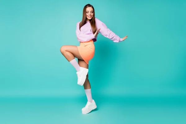 Foto de perfil de longitud completa de la señora funky levantar la pierna buen humor disfrutar de fiesta bailando movimientos juveniles usar suéter de color púrpura recortado falda naranja zapatos calcetines aislados color verde azulado fondo —  Fotos de Stock