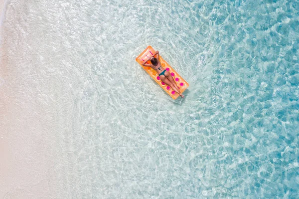 Üstte yüksek açılı hava drone görüntüsü. Sıska, sportif, çekici kız kauçuk yatakta yüzüyor. Temiz, doğal deniz suyunun keyfini çıkar. — Stok fotoğraf