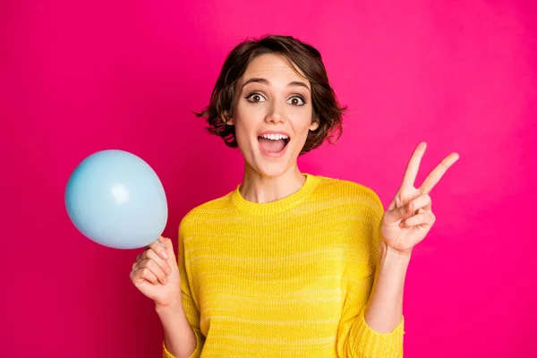 Porträt von energischen aufgeregt lustige Mädchen halten Ballon machen V-Zeichen genießen Jubiläums-Party tragen helle Pullover isoliert über lebendigen Farbhintergrund — Stockfoto