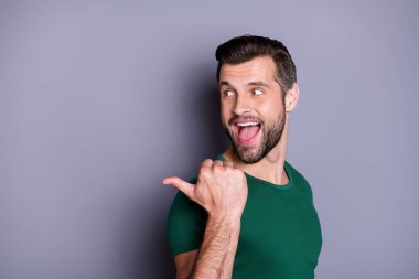 Cloeup profile photo of attractive guy good mood direct thumb finger side empty space show cool offer shopping price wear casual green t-shirt isolated grey color background clipart