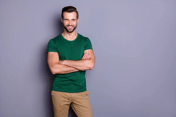 Foto van aantrekkelijke man zakenman macho uiterlijk nette kapsel borstel glimlachen stralen goed humeur armen gekruist dragen casual groene t-shirt broek geïsoleerde grijze kleur achtergrond — Stockfoto