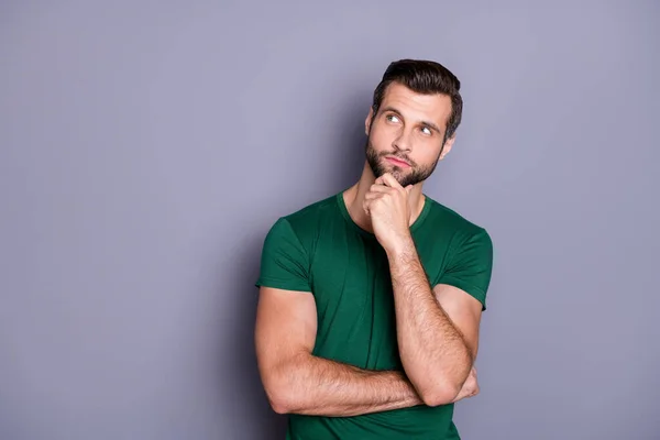 Foto de atractivo chico barbudo guapo sostener el brazo en la barbilla buscar espacio vacío se preguntaba inteligente persona creativa usar casual verde camiseta aislado gris color fondo — Foto de Stock