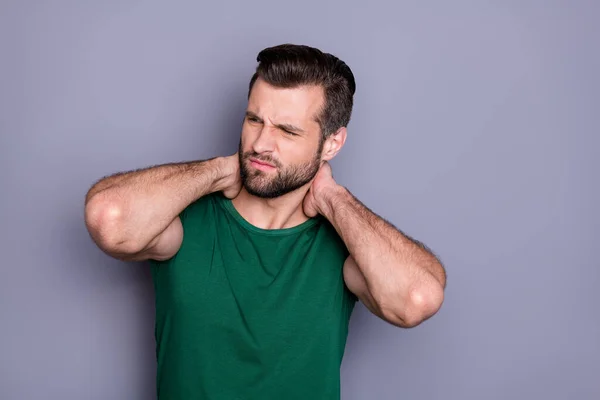 Retrato de tipo frustrado tocando el cuello de la mano tienen músculo estiramiento después de entrenamiento deportivo desgaste ropa verde aislado sobre fondo de color gris — Foto de Stock