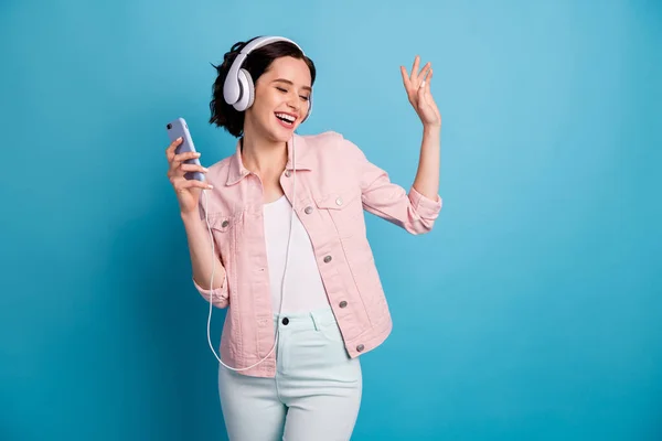 Foto av vacker glad dam hålla telefon lyssna cool modern teknik hörlurar ögon stängda njuta av musik dans bära casual rosa jacka byxor isolerad blå färg bakgrund — Stockfoto