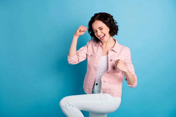 Photo of beautiful crazy lady short black hairdo raise hands fists celebrating winning match game football team supporter wear casual pink jacket pants isolated blue color background — Stock Photo, Image