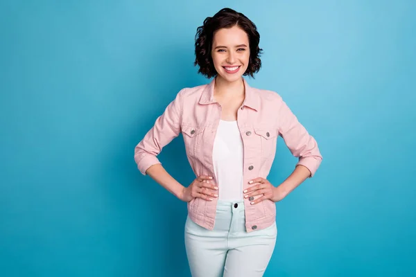 Foto de senhora bonita atraente curto penteado preto com raios de dentes sorrindo braços de bom humor por lados rua olhar desgaste casual rosa jaqueta de ganga isolado azul cor de fundo — Fotografia de Stock